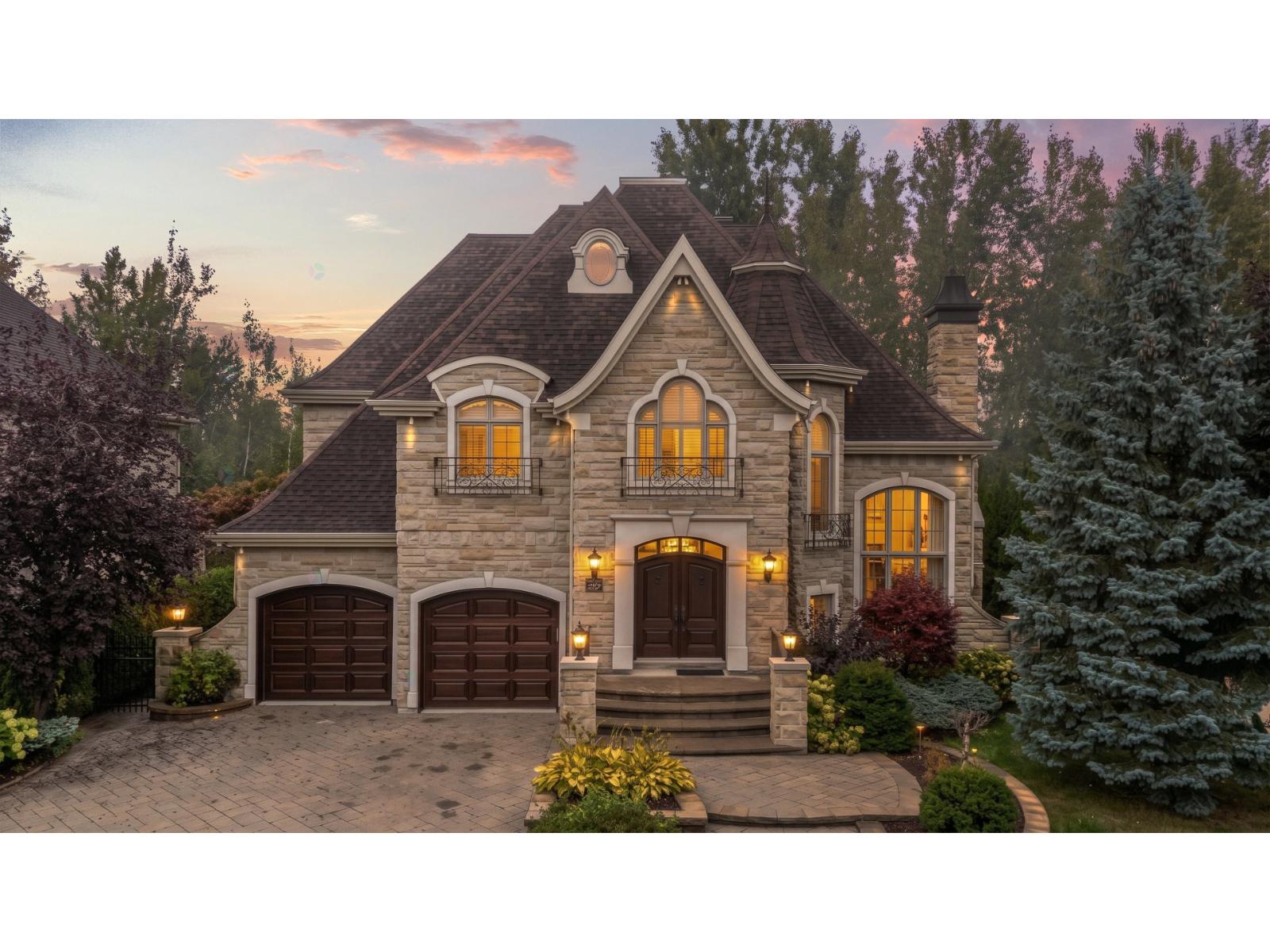 Maison individuelle à Blainville avec façade en pierre, double garage et fenêtres éclairées au crépuscule